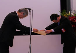 山本会長から表彰状を受け取る、東芝　環境推進部の竹山グループ長の写真