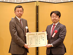 「審査委員長の横浜国立大学大学院・八木裕之教授（左）から表彰状を受け取る様子」のイメージ