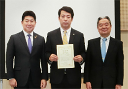 「認定証を受けた小向事業所 石山副所長（写真中央）」の写真