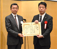 「受賞式 審査委員長（左）と小向事業所 石山副所長（右）」の写真