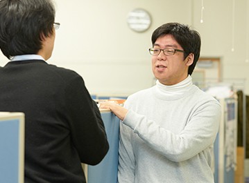 同僚と会話する橋本さんの写真