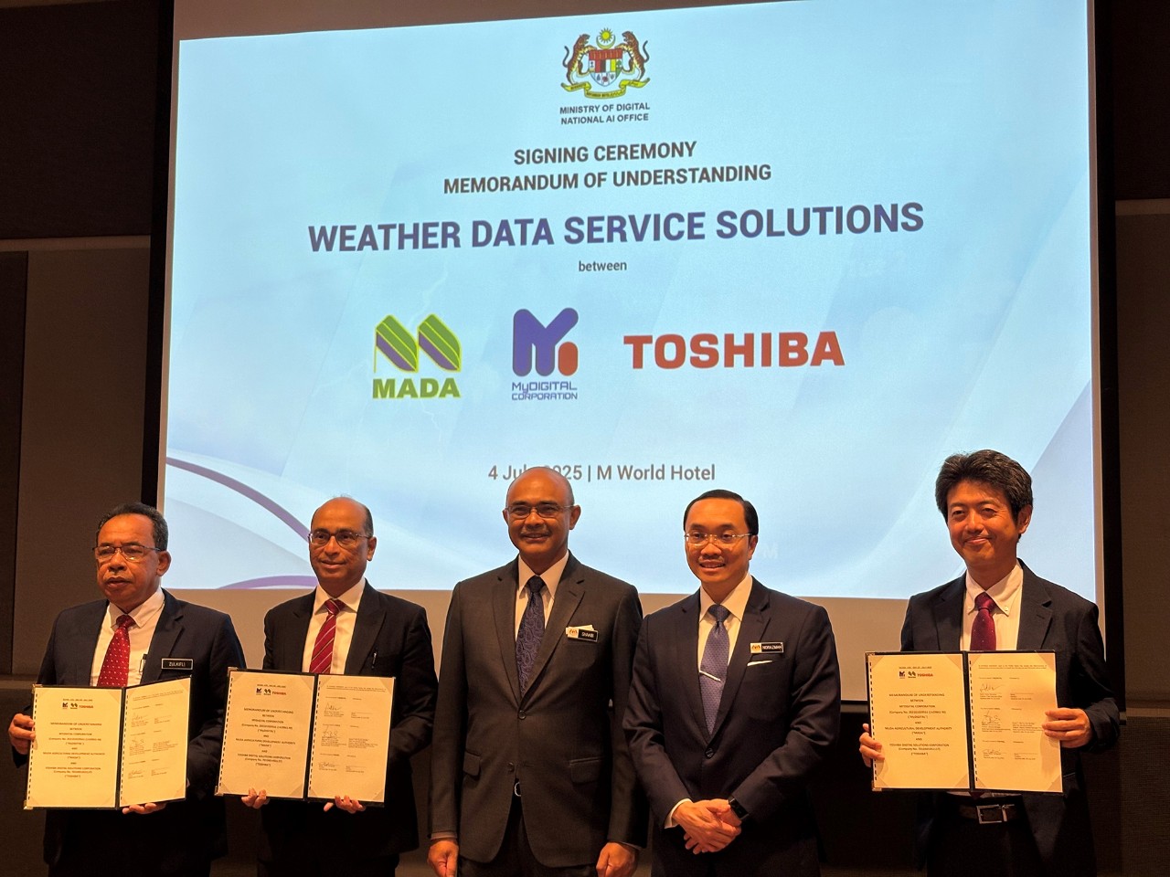 The signatories hold the signed MoU: Zulkifli bin Romli, General Manager of MADA; Adrian Marcellus, CEO of MyDIGITAL Corporation; and Naoki Yamaguchi, General Manager of ICT Solutions Division, Toshiba Digital Solutions Corporation (left to right)